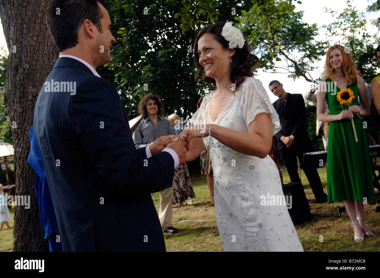 Bräutigam legt Ring auf Bräute Finger ein paar wiederum den Gästen nach Abschluss eine standesamtliche Trauung in Garsington Oxfordshire Stockfoto