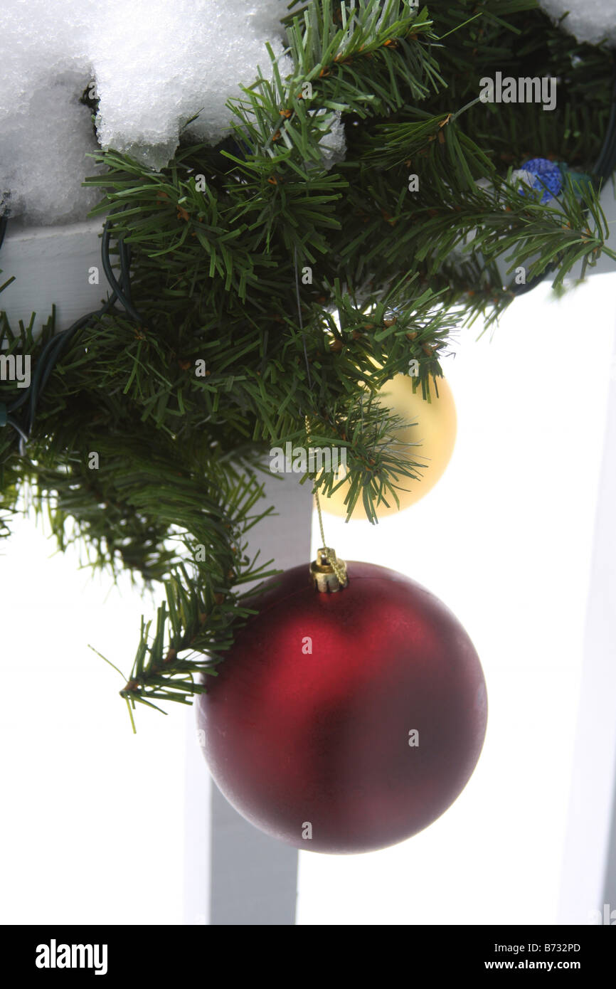 Ornamente aus eine Weihnachtsgirlande hängen eine Veranda Geländer mit Schnee Stockfoto
