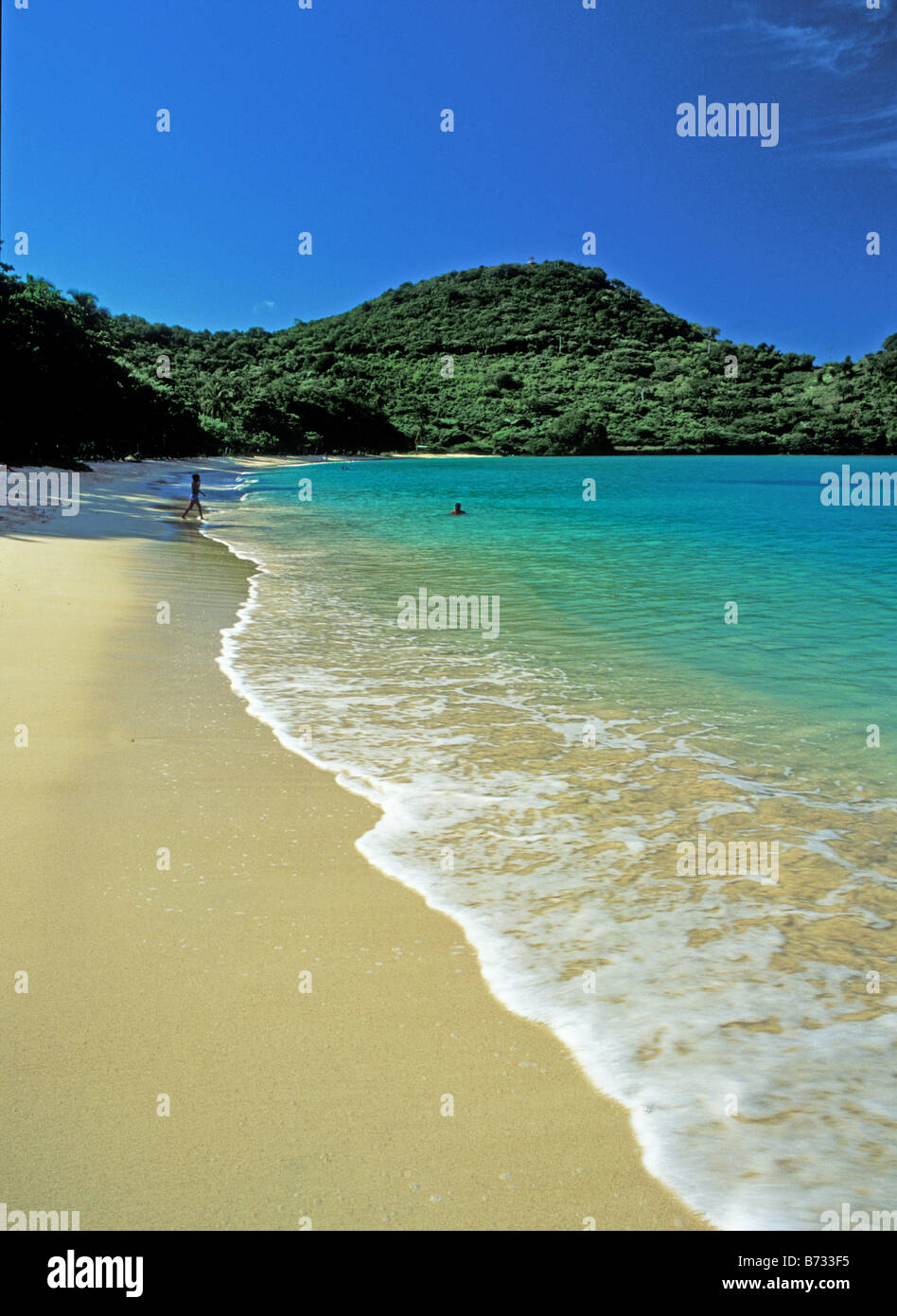 Goldenen Sandstrand und klaren, türkisfarbenen Wasser mit grünen Hügel im Hintergrund Stockfoto