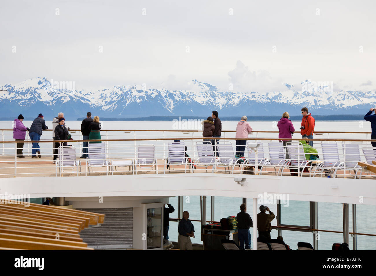 Kreuzfahrtpassagiere, die am Schiffsgeländer stehen und die schneebedeckten Berge sehen, segeln auf der Inside Passage in Alaska Stockfoto