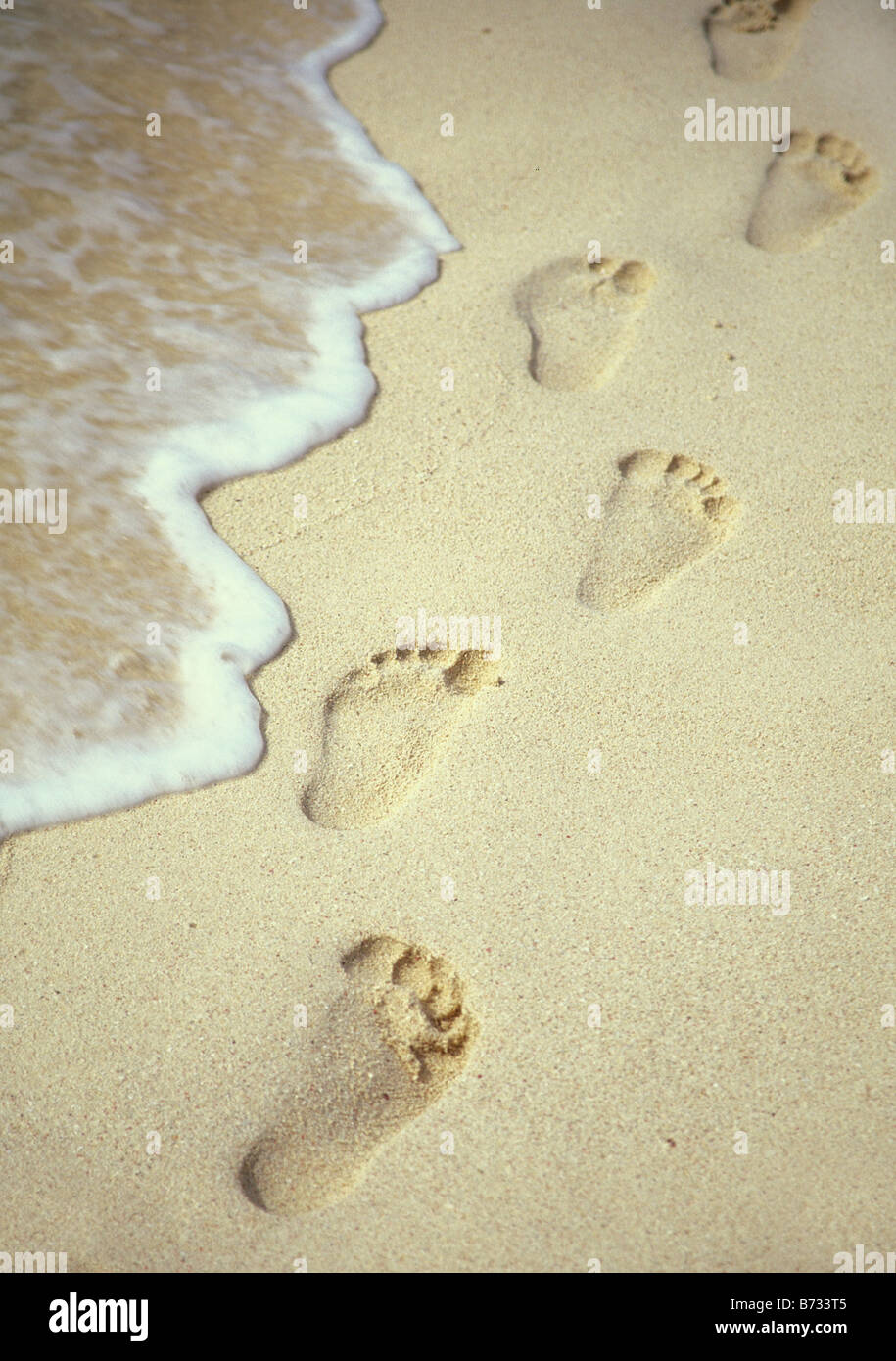 Fußspuren im Sand entlang einer Welle Stockfoto