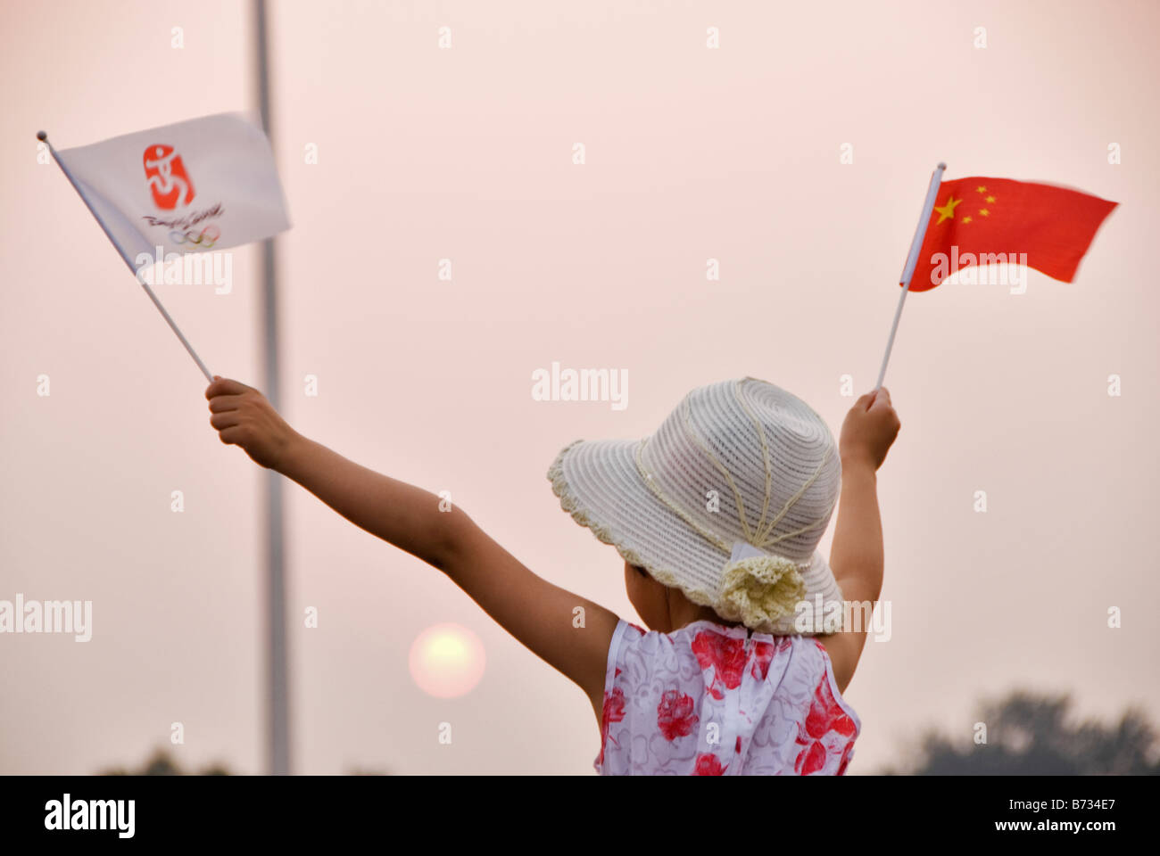 Mädchen mit Chinesse und Olympische Fahnen am Sonnenuntergang Platz des himmlischen Friedens Peking China Stockfoto
