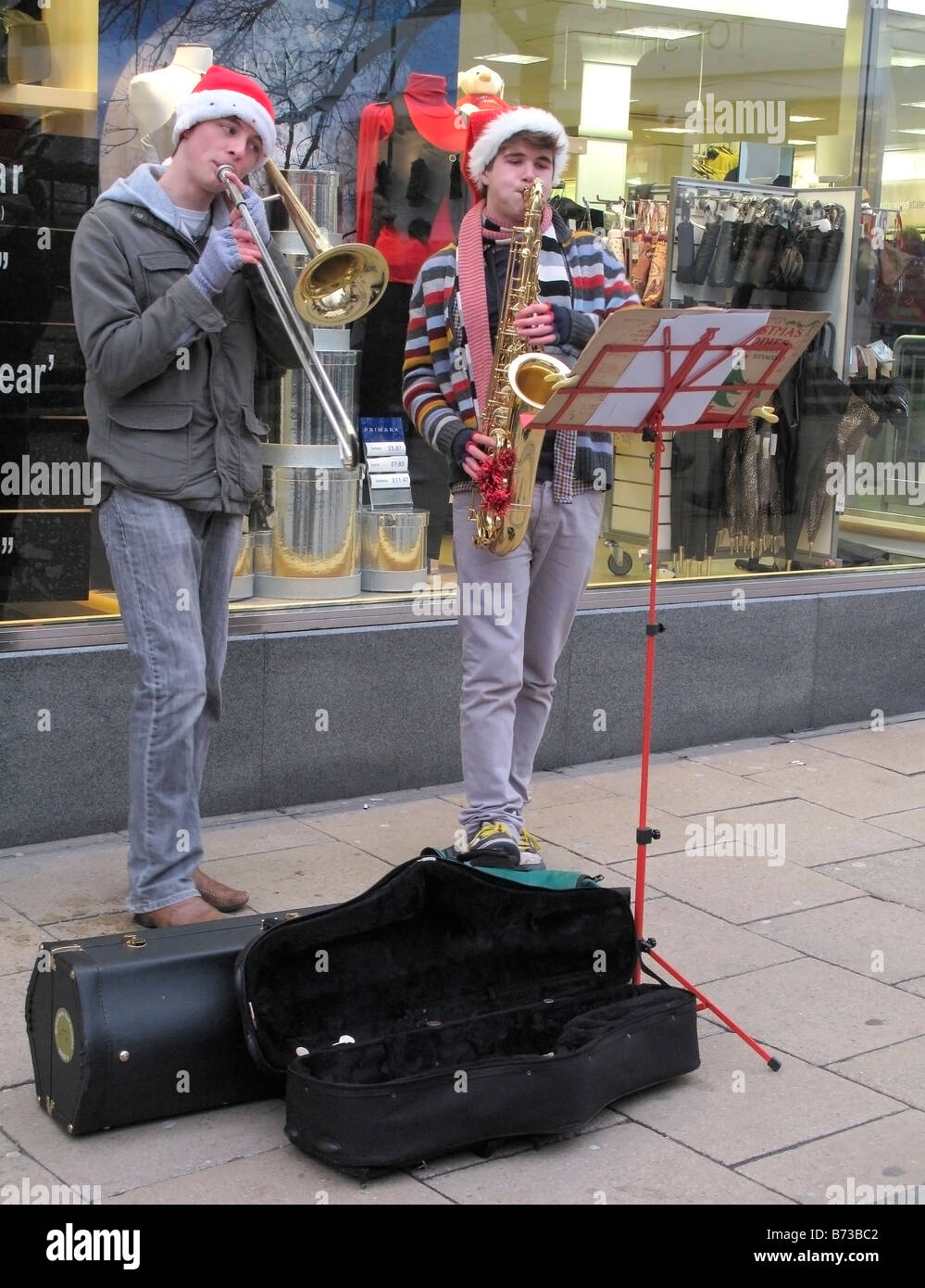 Zwei Burschen als Straßenmusikant Geld spielen Weihnachtslieder auf Posaunen auf der Straße von Norwich Weihnachtszeit Stockfoto