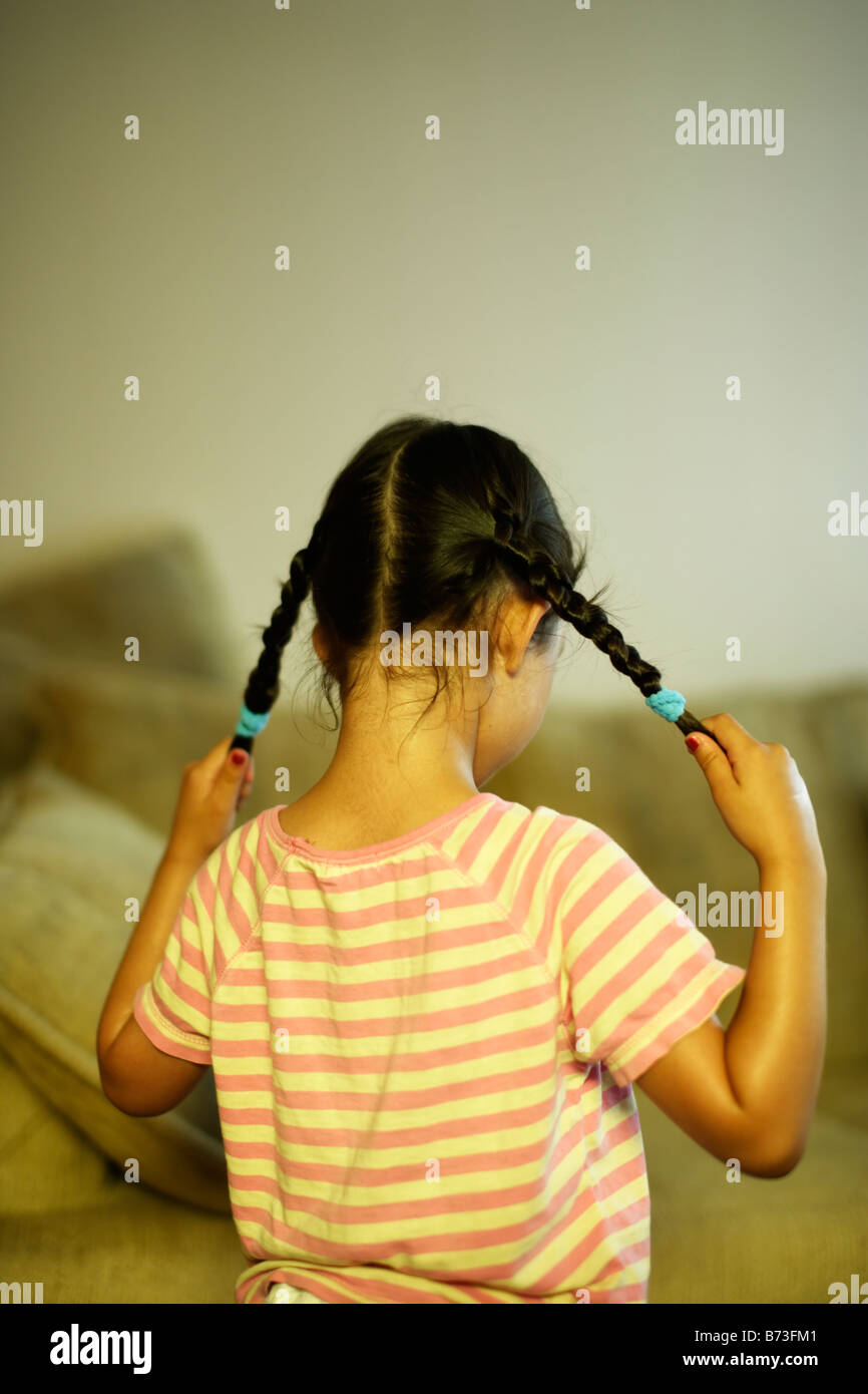 Fünf Jahre altes Mädchen zieht ihren Zöpfen Stockfoto
