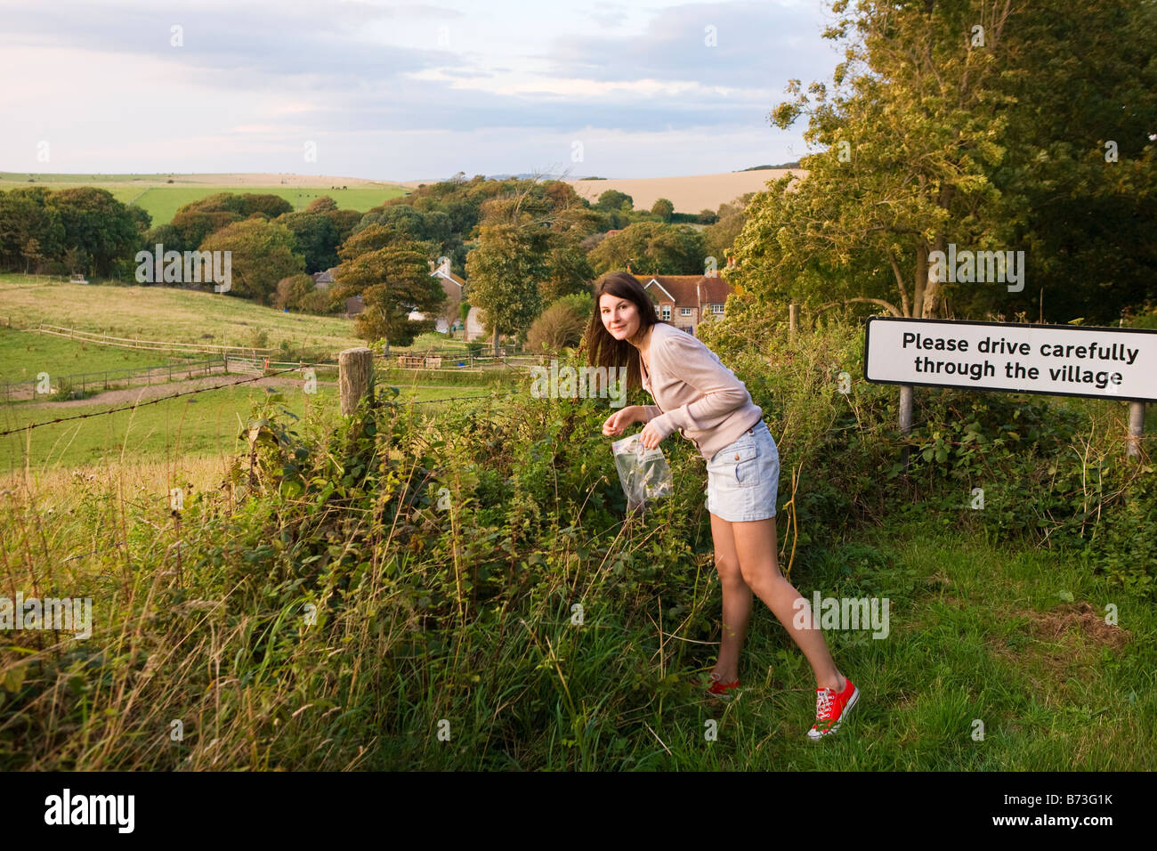 Porträt einer jungen Frau, die Kommissionierung wilden Brombeeren nur außerhalb eines kleinen Dorfes in England Stockfoto