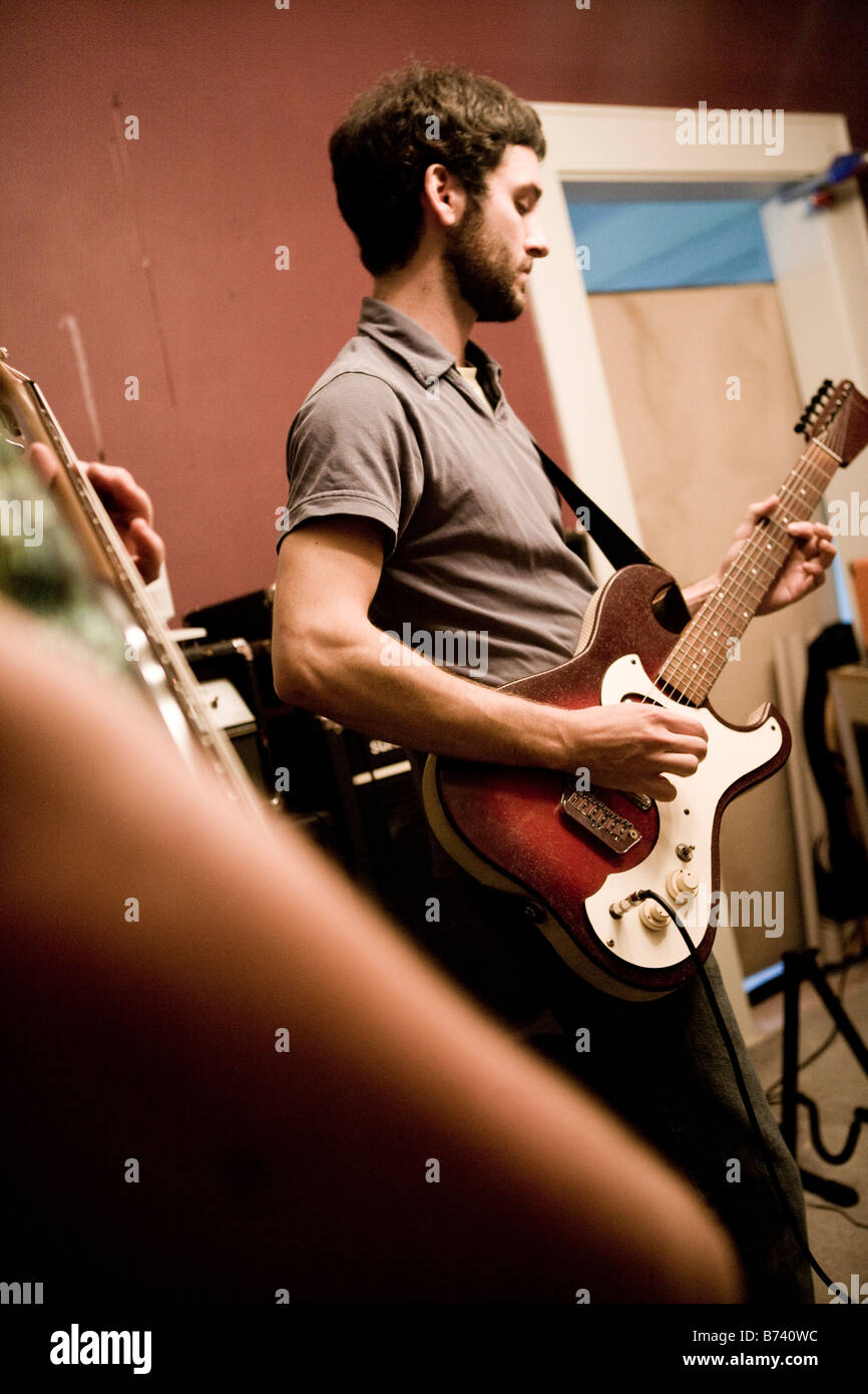 Junger Mann spielt Gitarre mit band Stockfoto