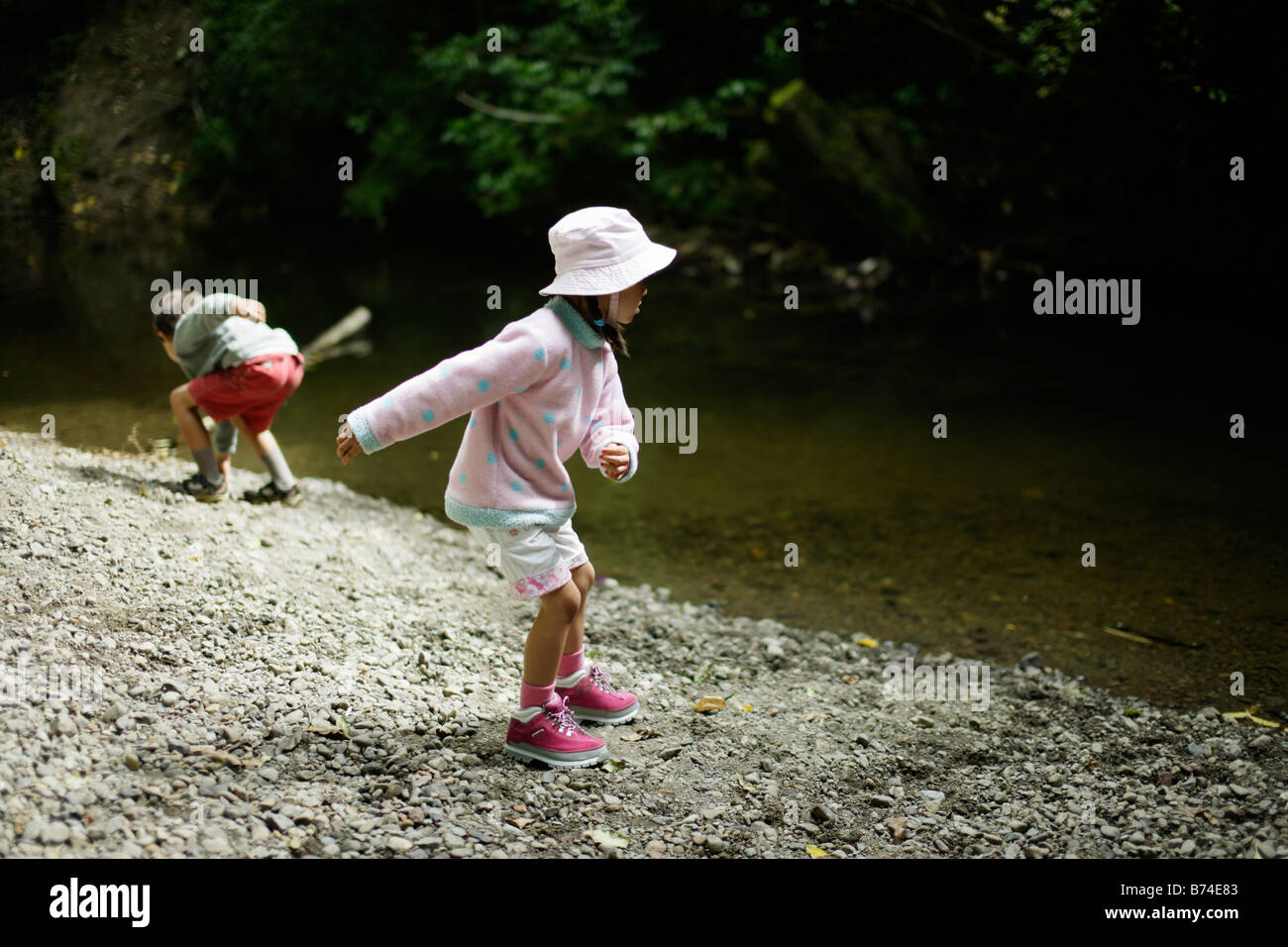 Kinder werfen mit Steinen in Stream fünf Jahre altes Mädchen und sechs Jahre alten Bruder Stockfoto