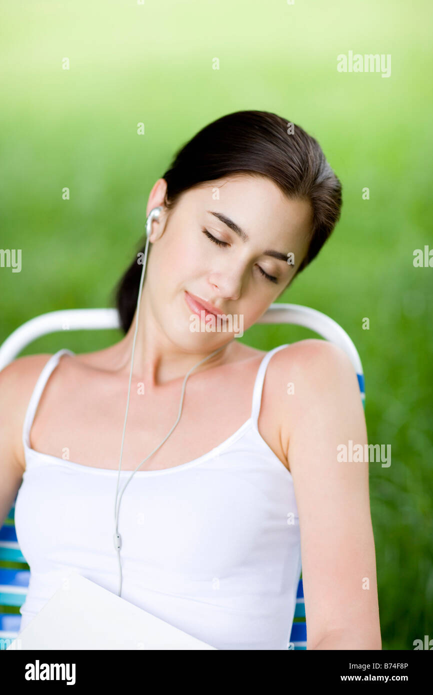 Junge Frau liegt auf Liegestuhl hören MP3 Player Augen geschlossen Stockfoto