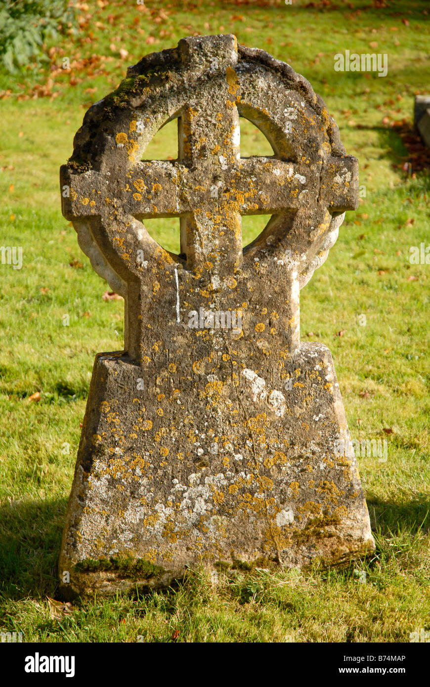 Alten Grabstein auf einem Friedhof mit Kreuz eingeschlossen in einen Kreis und Flechten, die auf ihm wachsen. Stockfoto