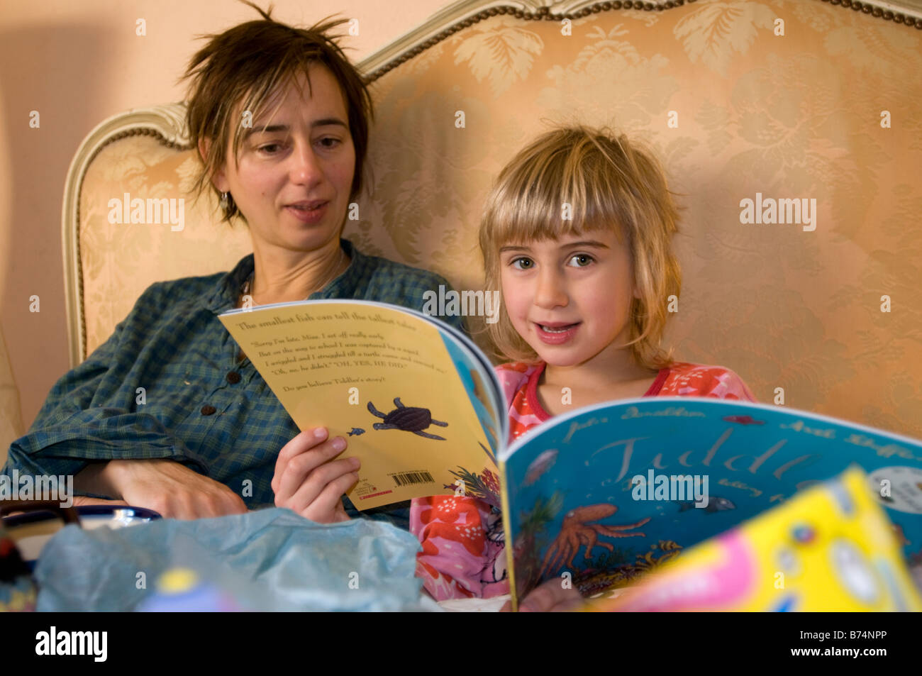 Eine 6-jährige an ihrem Geburtstag mit ihrer müde Mutter ihr neues Buch zu lesen. Stockfoto