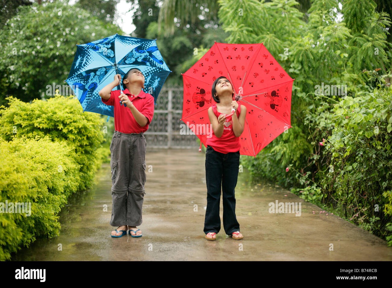 Jungen und Mädchen mit Regenschirm suchen schwerer Regenfälle in den Himmel Stockfoto