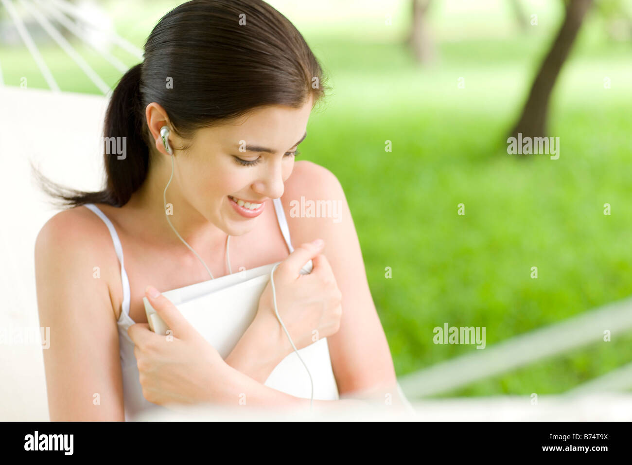 Junge Frau sitzt auf Hängematte Buch Augen geschlossen halten Stockfoto