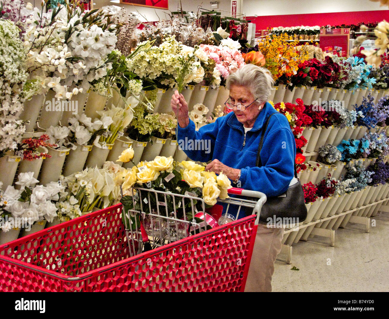 Eine ältere Frau Kunde wählt eine Auswahl an künstlichen Blumen in einem Aliso Viejo CA-Geschenk-Shop Stockfoto