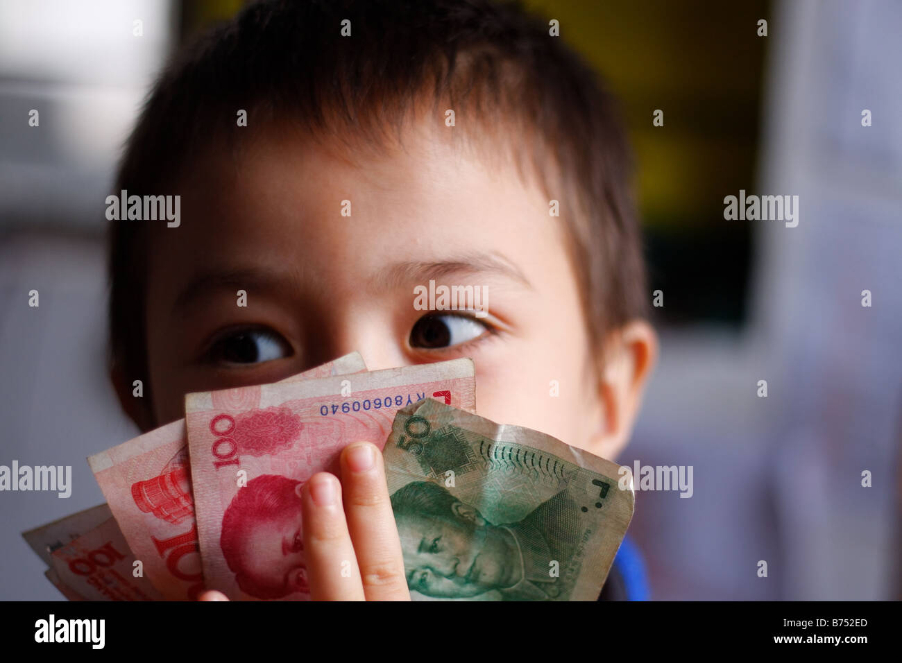 6 Jahre alten asiatischen kaukasischen chinesische American Boy mit chinesisches Geld in jeder Hand in seinem Haus in China Lucky Money spielen Stockfoto