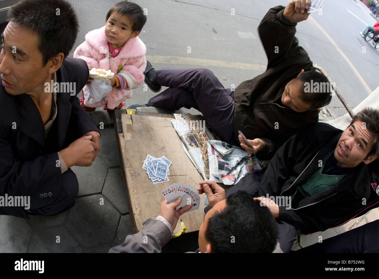 Gruppe von Straße Wokers Chinese Poker zusammen mit kleines Mädchen auf Straßen der Oberschicht Gemeinschaft spielen Stockfoto