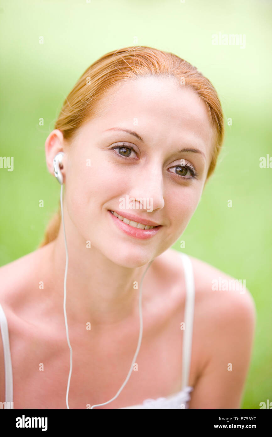 Junge Frau hören mp3-Player, Lächeln, Porträt Stockfoto