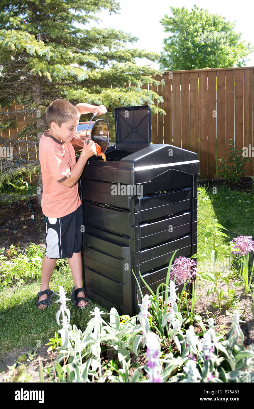 Junge mit Kompost-Eimer neben Komposter im Hinterhof, Winnipeg, Manitoba, Kanada Stockfoto