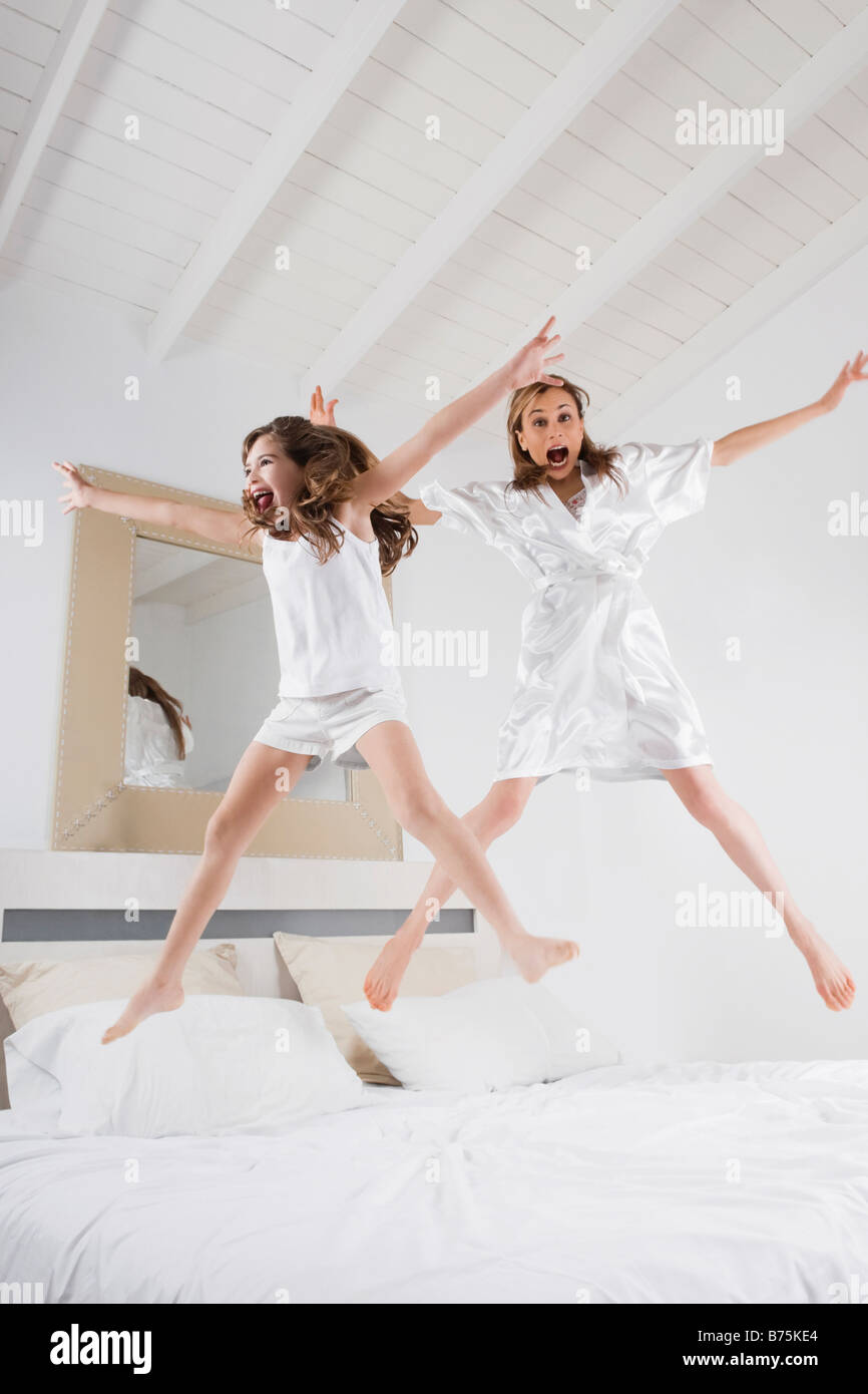 Mitte Erwachsene Frau mit ihrer Tochter auf dem Bett springen Stockfoto