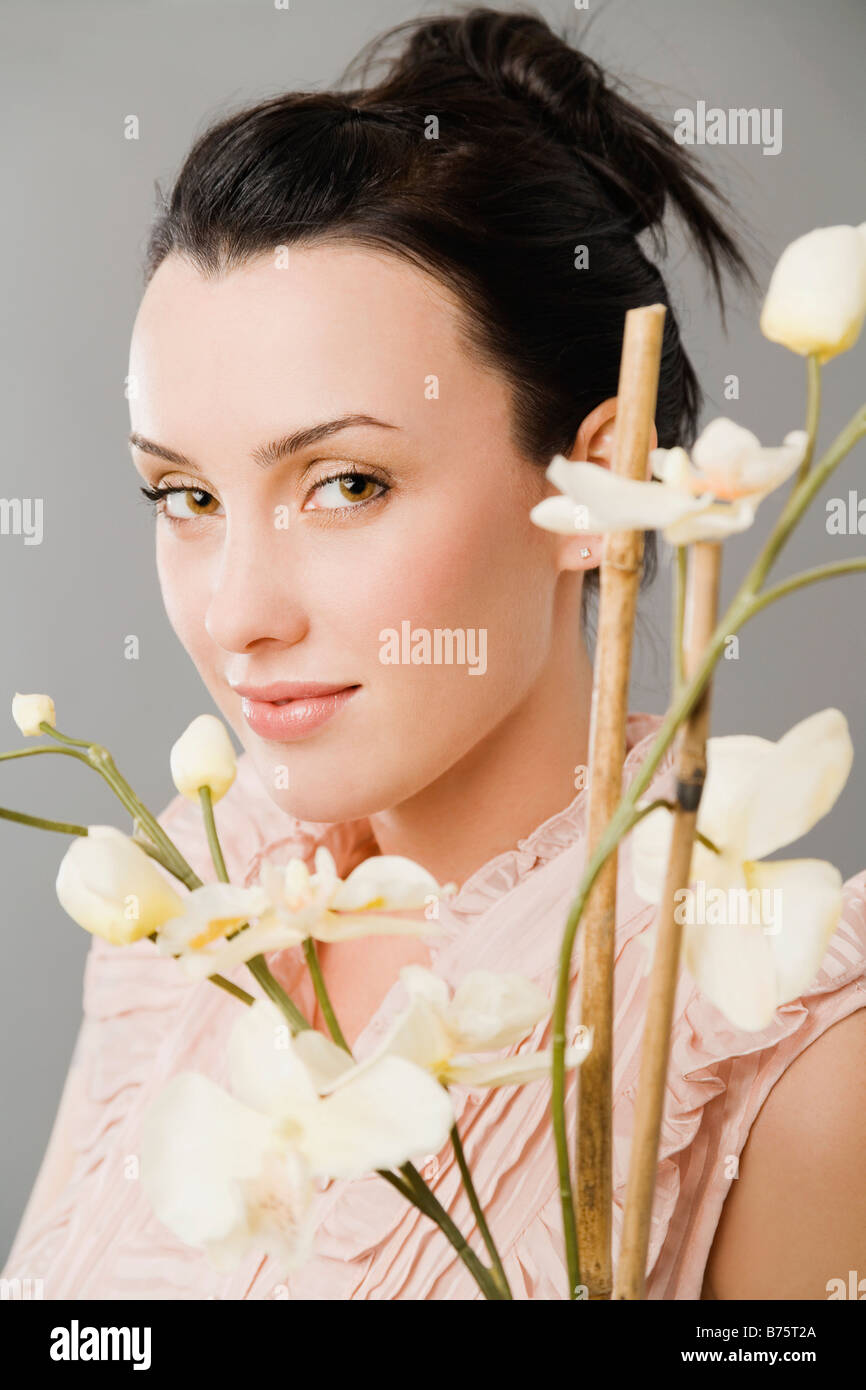 Porträt einer jungen Frau lächelnd hinter Blumen Stockfoto