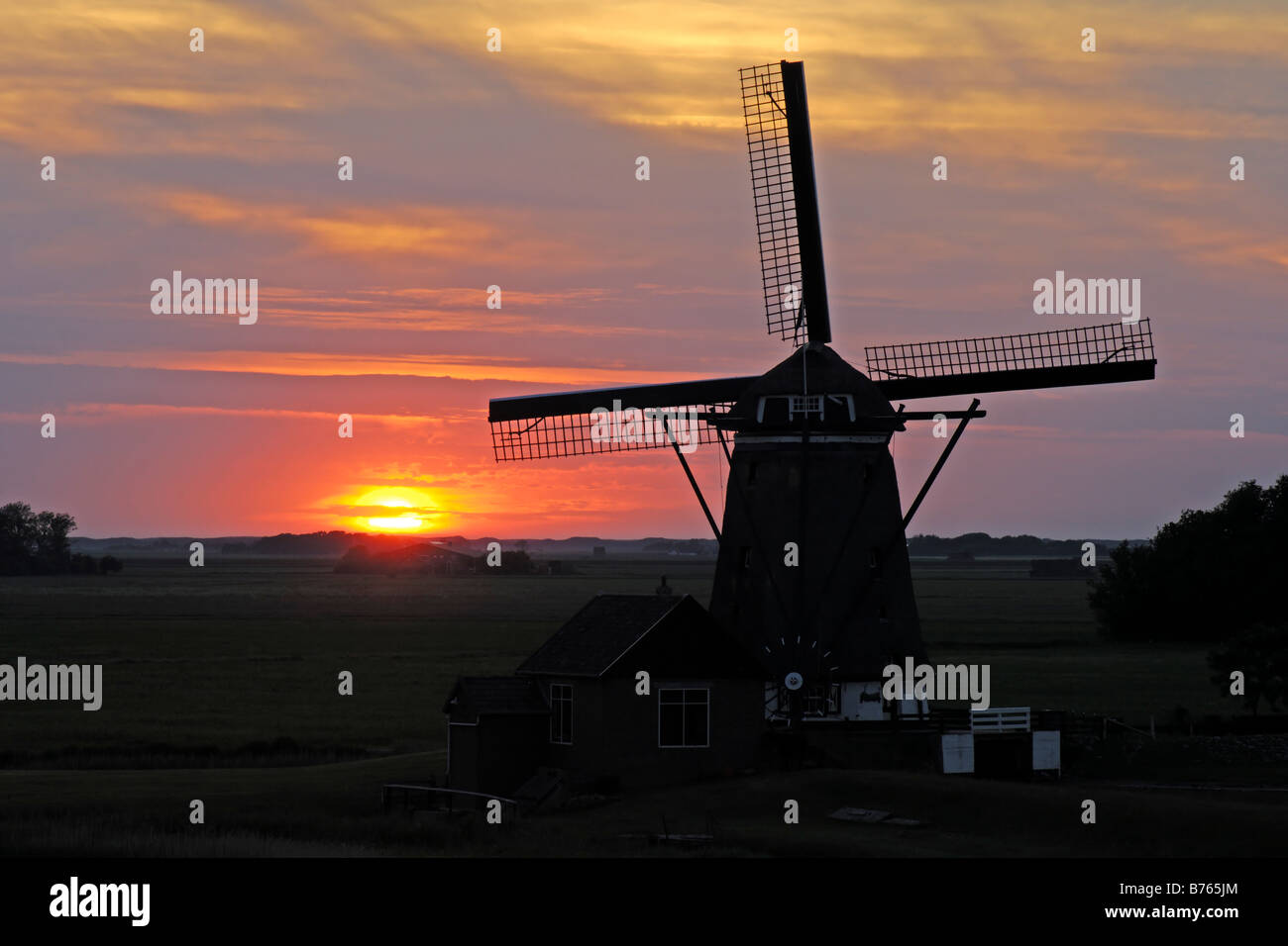 holländische Windmühle roten Sonnenuntergang Hintergrundbeleuchtung Holland Texel Insel Sillhouette Abendrot Abendstimmung Stockfoto