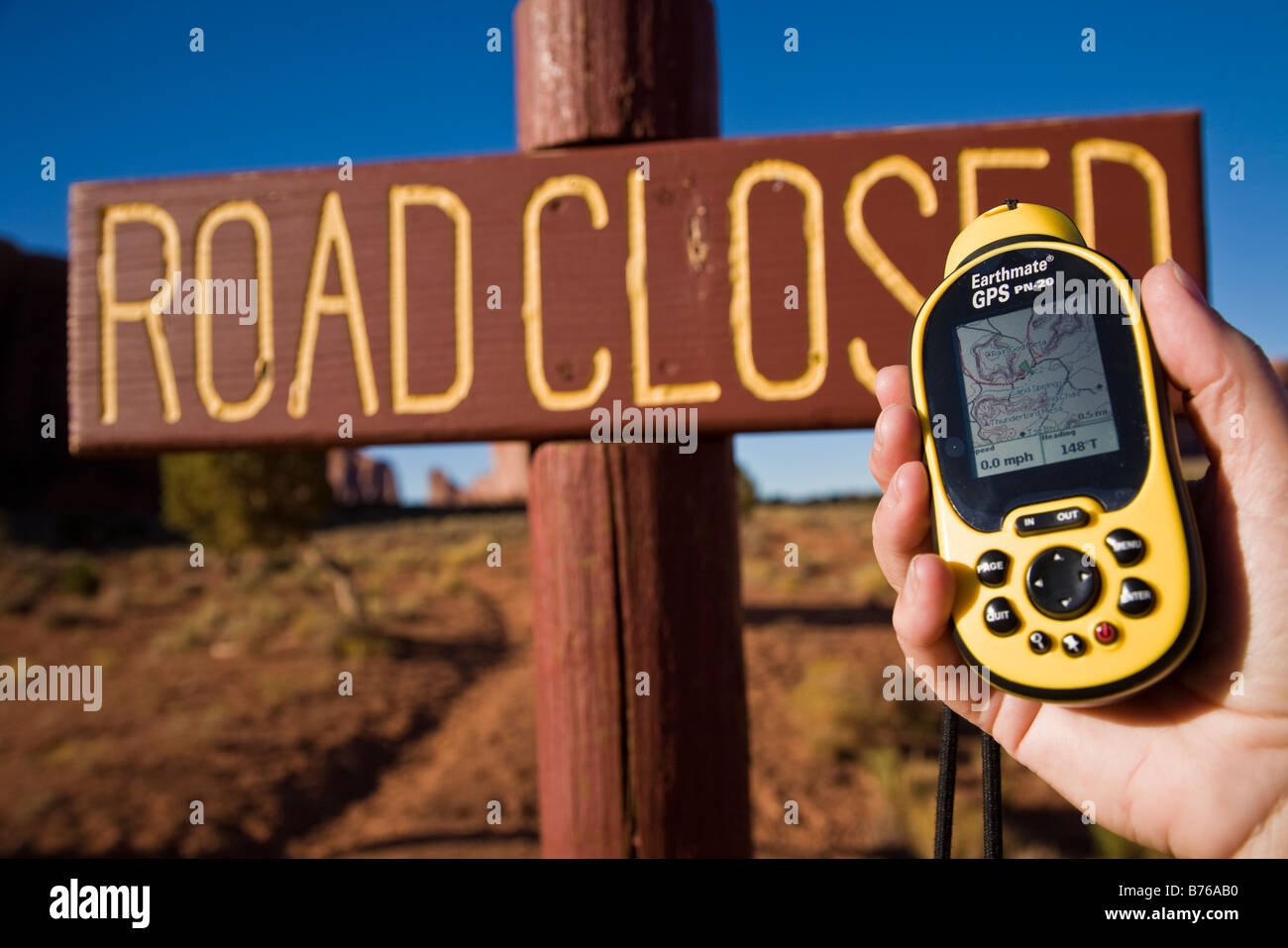 Globale Positioniereinheit Satelliten (GPS) statt einer mans Hand vor einem geschlossen Straßenschild, Monument Valley, Arizona, USA Stockfoto