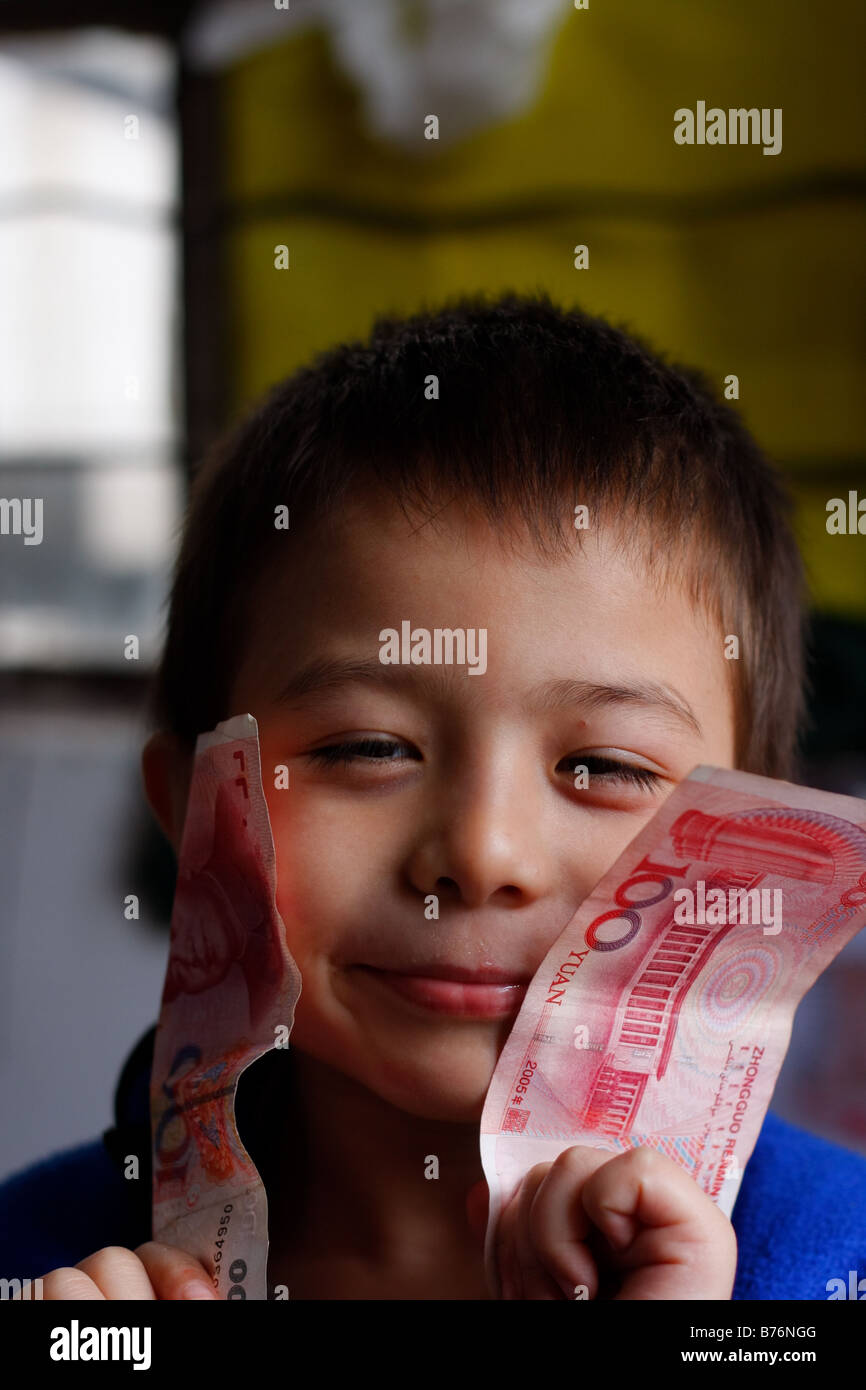6 Jahre alten asiatischen kaukasischen chinesische American Boy mit chinesisches Geld in jeder Hand in seinem Haus in China Lucky Money spielen Stockfoto