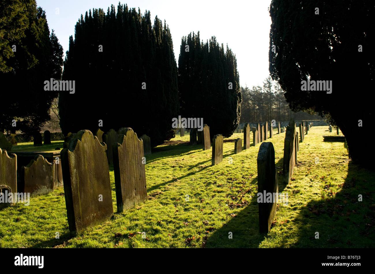 Kirche-Friedhof mit Grabsteinen und lange Schatten Stockfoto