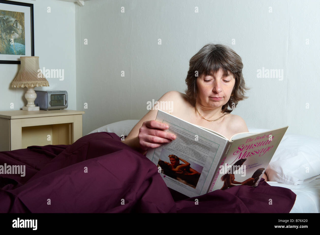 Mittlere gealterte Frau im Bett und las ein Buch über massage Stockfoto