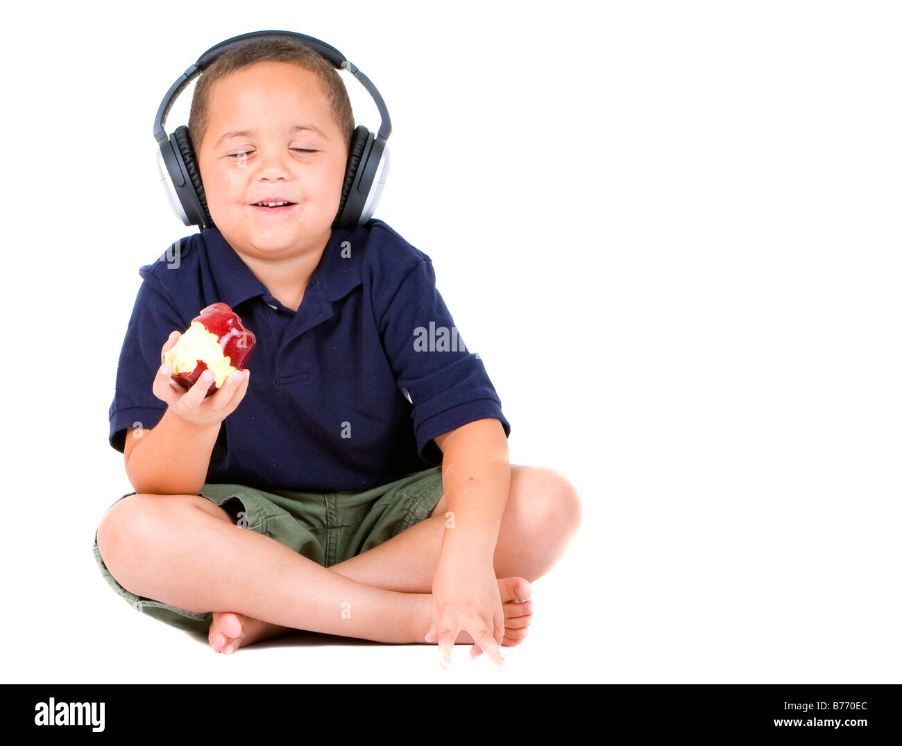 Fröhlicher Junge genießen einen Apfel und Musik hören Stockfoto