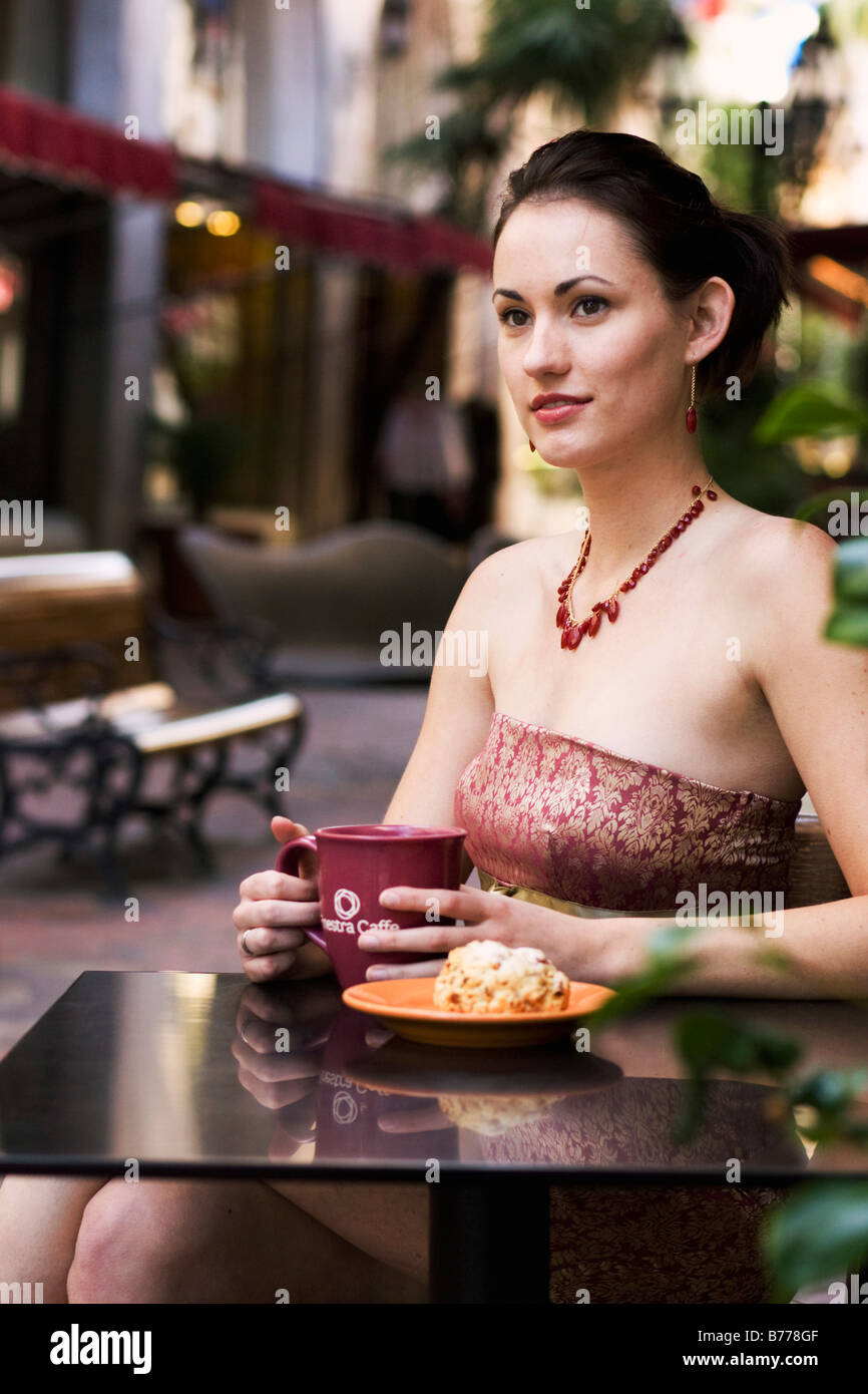 Junge Frau sitzt in einem Café im freien Tisch einen Cappuccino trinken Stockfoto