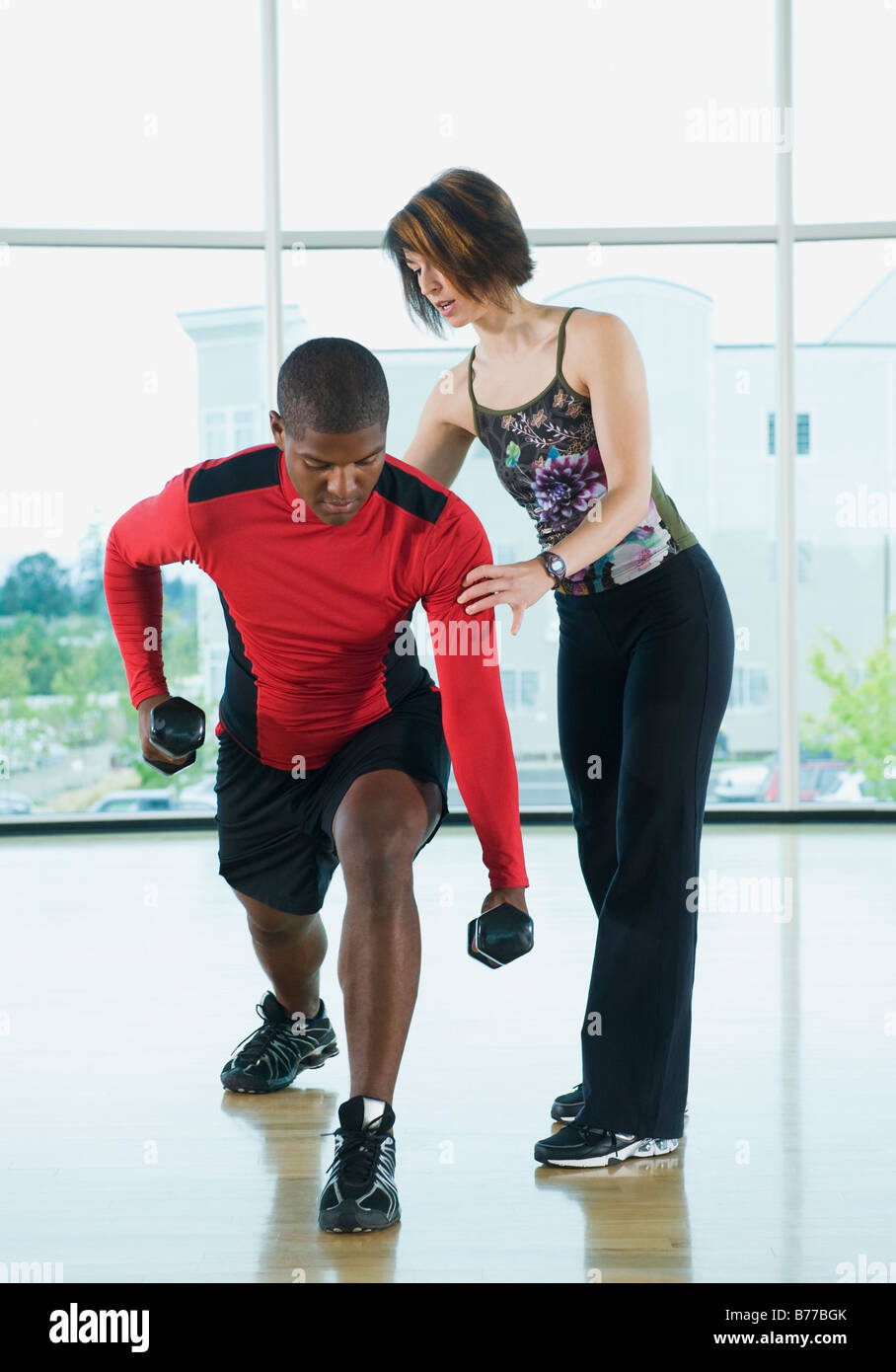 Fitness-Trainer hilft Mann Longe Hanteln Stockfoto