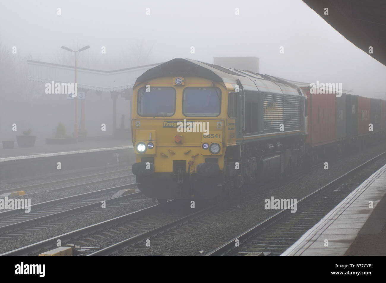 Güterzug auf der Durchreise Bahnhof im Winternebel, UK Stockfoto