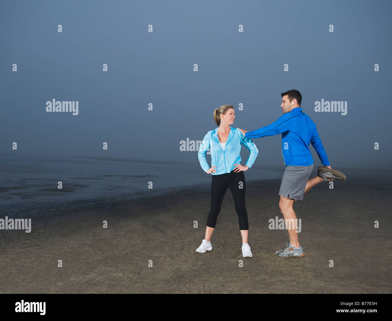 Paar am Strand dehnen Stockfoto
