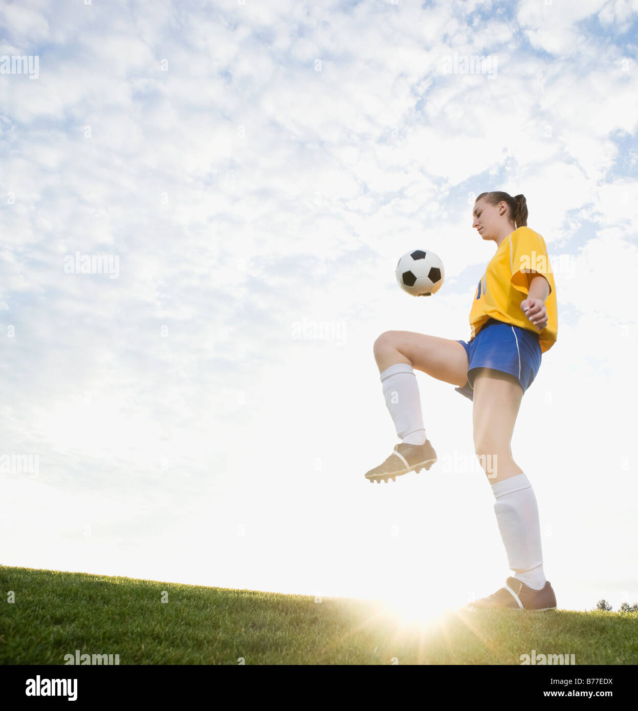Teenager-Mädchen Fußball auf Knie springt Stockfoto
