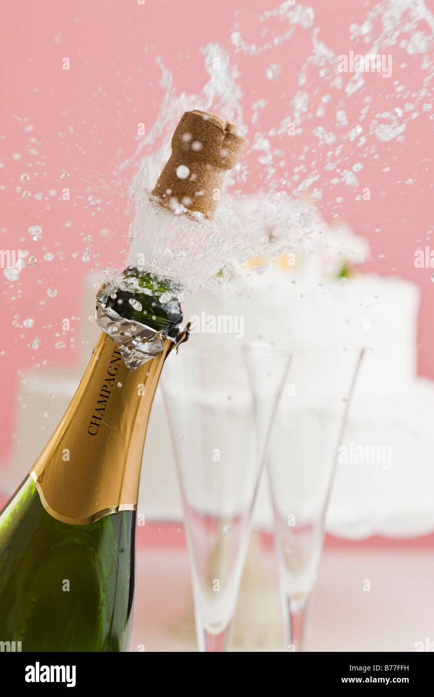 Kork aus Champagner-Flasche Hochzeitstorte Hintergrund explodieren Stockfoto