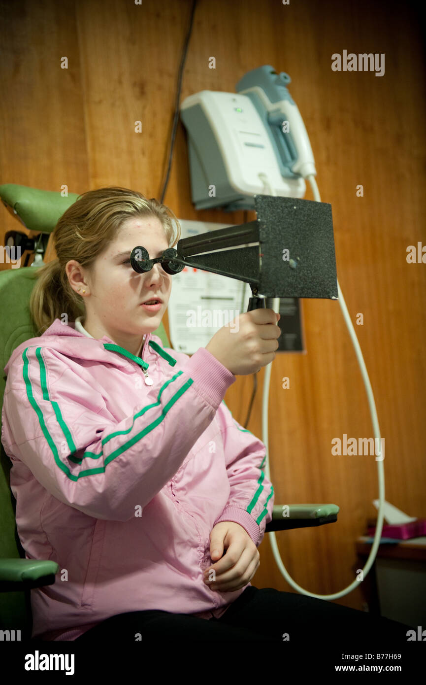 kurzsichtig Teenager-Mädchen hält ein MADDOX-Flügel mit ihren Augen von einem National Health Service Optiker UK geprüft Stockfoto