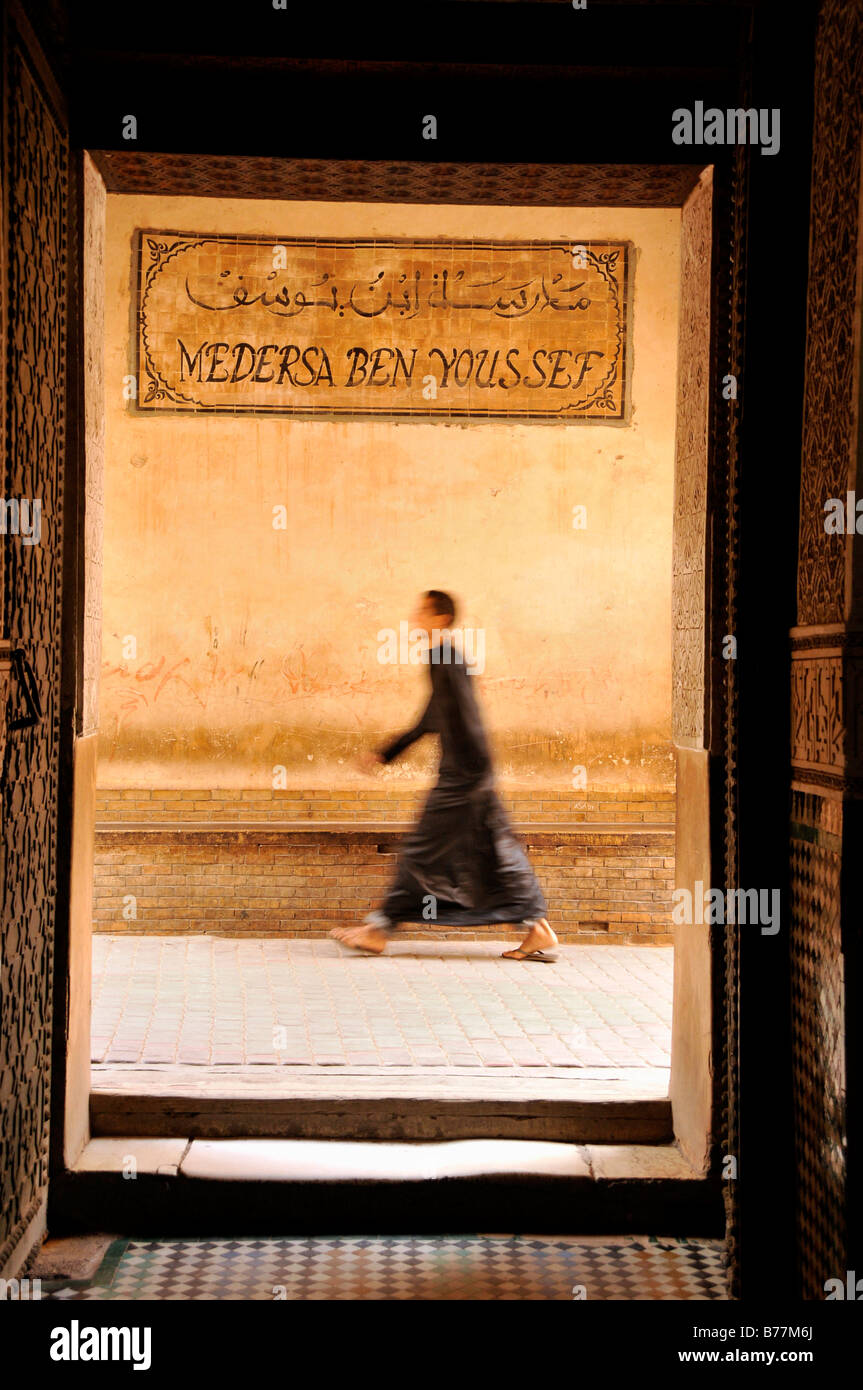 Mann trägt einen Mantel zu Fuß durch eine Gasse in Ben Youssef Madrasah, Koran-Schule im Stadtteil Medina von Marrakesch, Mo, USA Stockfoto