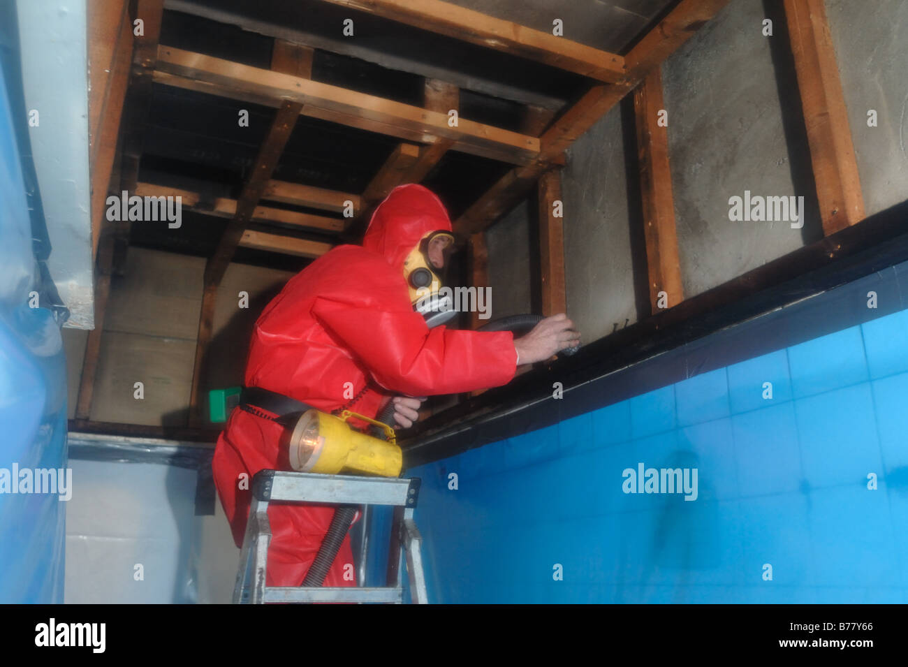 Mann in voller Schutzkleidung innerhalb einer sicheren Umgebung Aufräumarbeiten nach Asbestsanierung Exeter Stockfoto