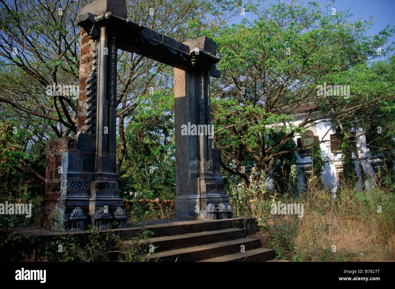 Adil Shah Palast Tor Ruine isolierte Tor Mauerwerk Schritte zugewachsen Haus mit Fensterläden hinter OLD GOA GOA Indien Stockfoto