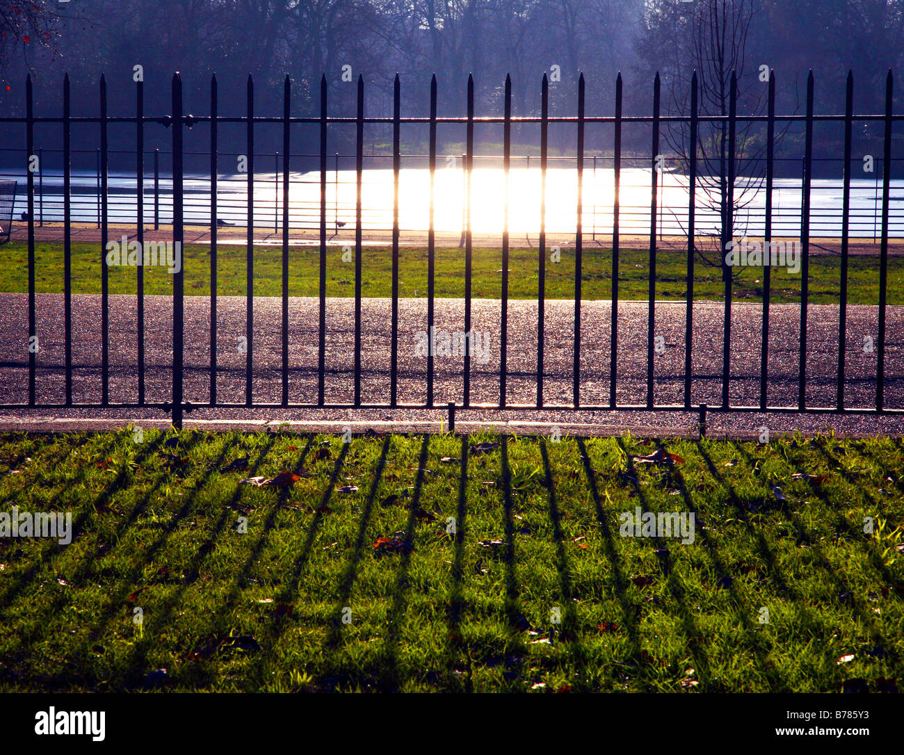 Park-Geländer im Battersea Park mit Sonne und Teich im Hintergrund. Stockfoto