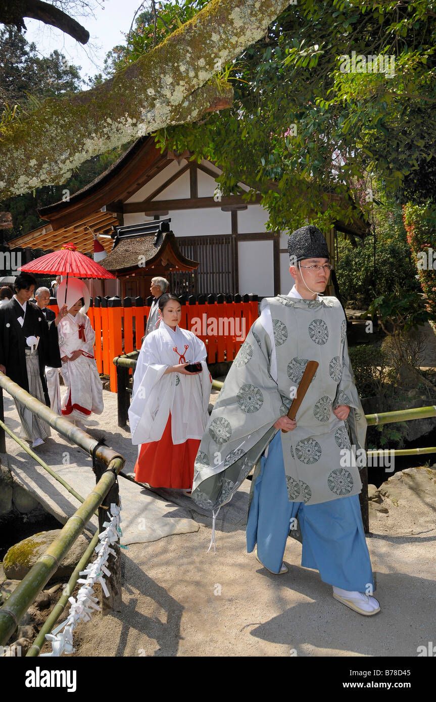 Brautpaar auf ihrem Weg zu einer Shinto Zeremonie mit einer Miko shrine Maiden und ein Shinto-Priester am Kamigamo Schrein, Kyoto, Stockfoto