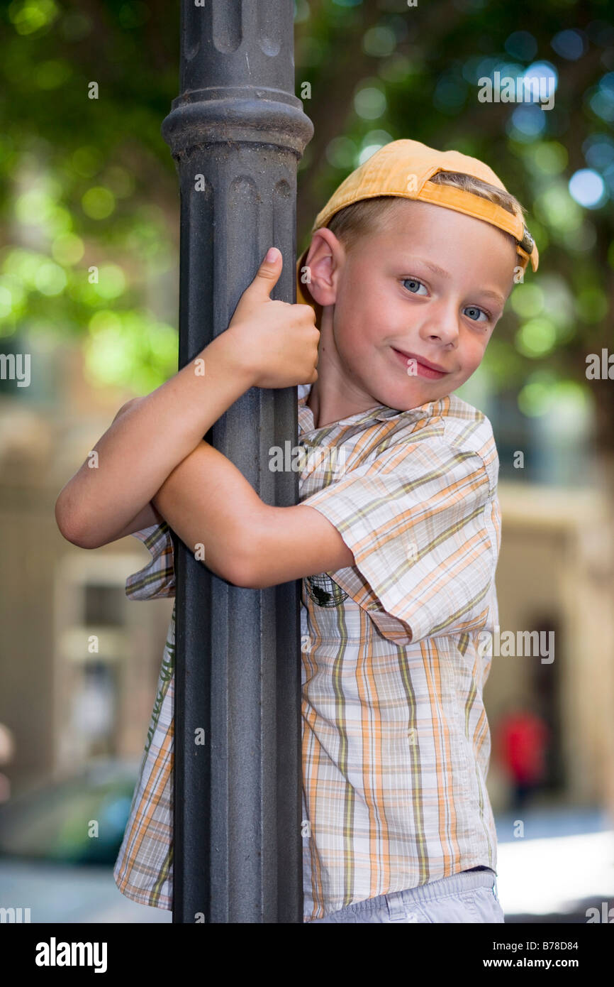 6-jähriger Junge klettern einen Laternenpfahl Stockfoto