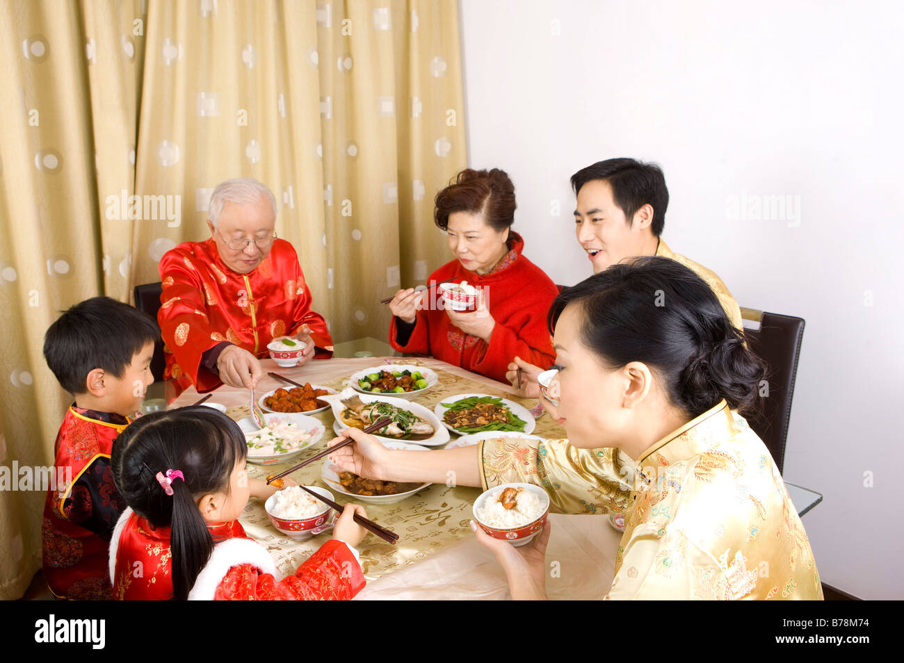 Familienmitglieder in traditioneller Kleidung beim Abendessen zusammen Stockfoto