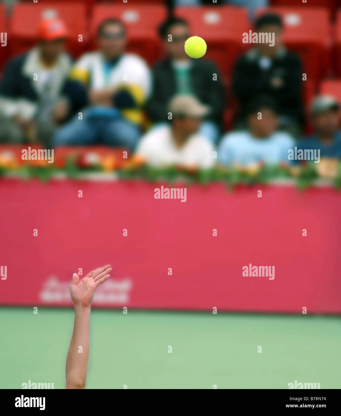 Ein Tennis-pro-Projekte den Ball in der Luft vor eine große Menge von Zuschauern (Gesichter verdeckt von Blur). Stockfoto