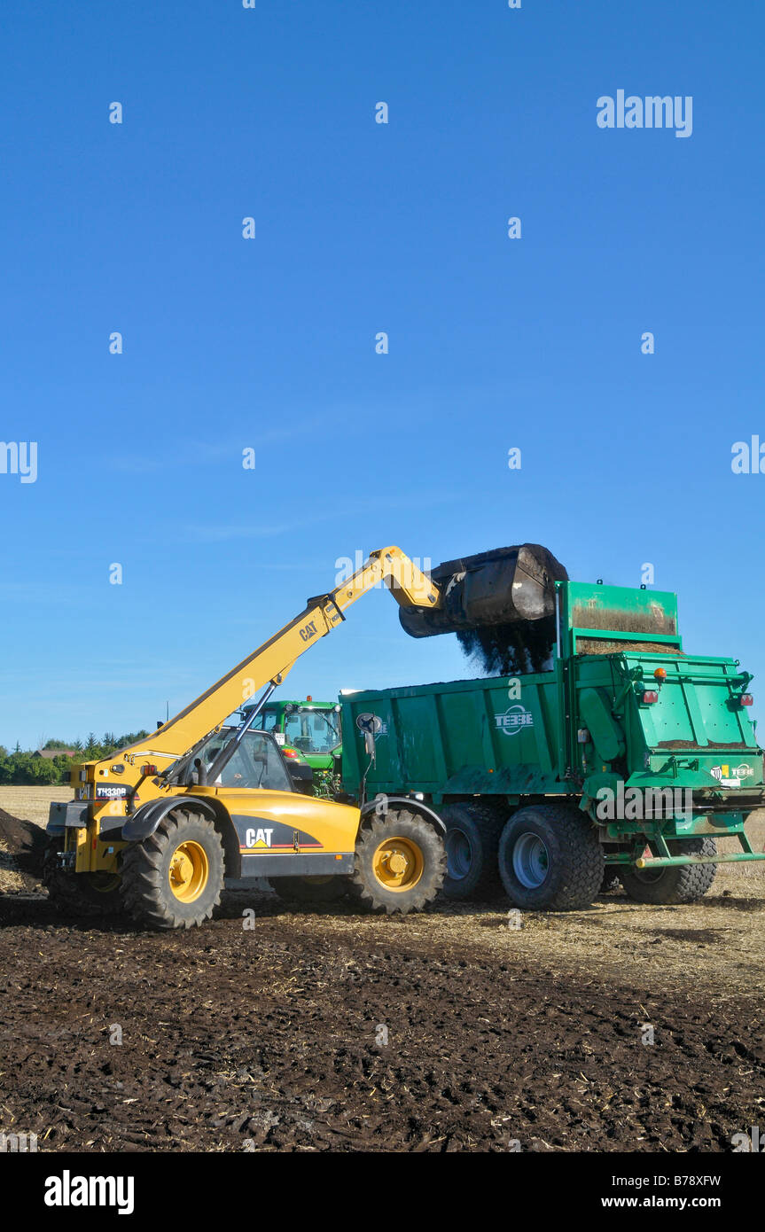 Eine Katze Teleskoplader (TH 330 B) mit einem Kompost Spreader gefüllt. Stockfoto