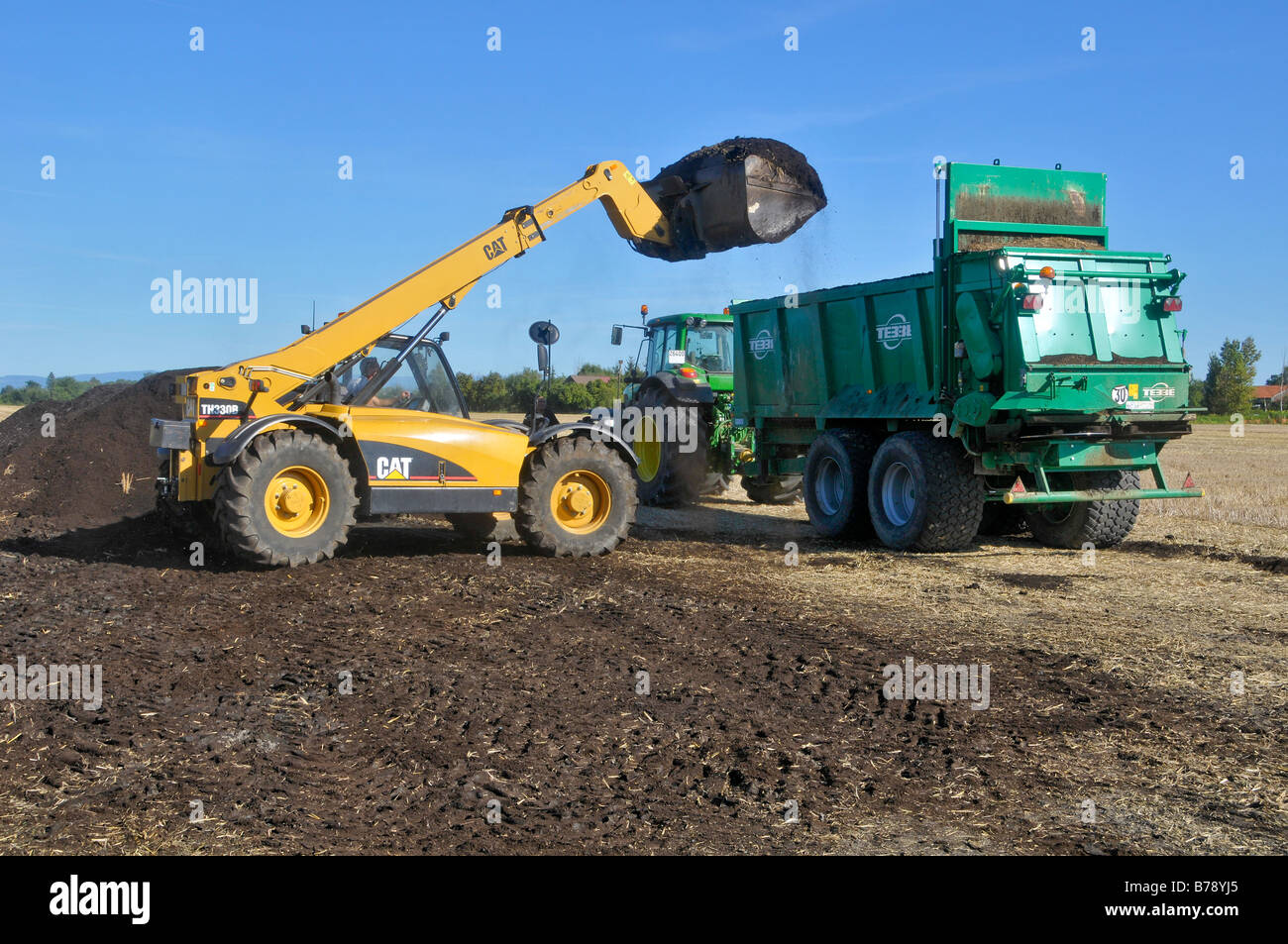 Eine Katze Teleskoplader (TH 330 B) mit einem Kompost Spreader gefüllt. Stockfoto