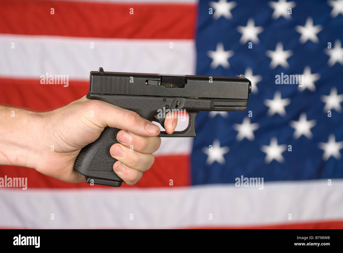 Ein Mann zeigt seine Semi automatische Pistole gegen eine amerikanische Flagge Stockfoto