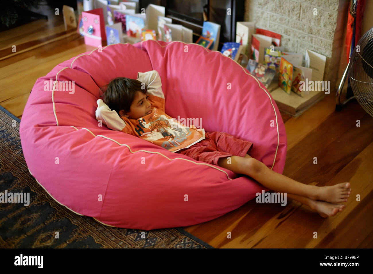 Sechs Jahre alter Junge sitzt in pink Sitzsack und Uhren tv Stockfoto