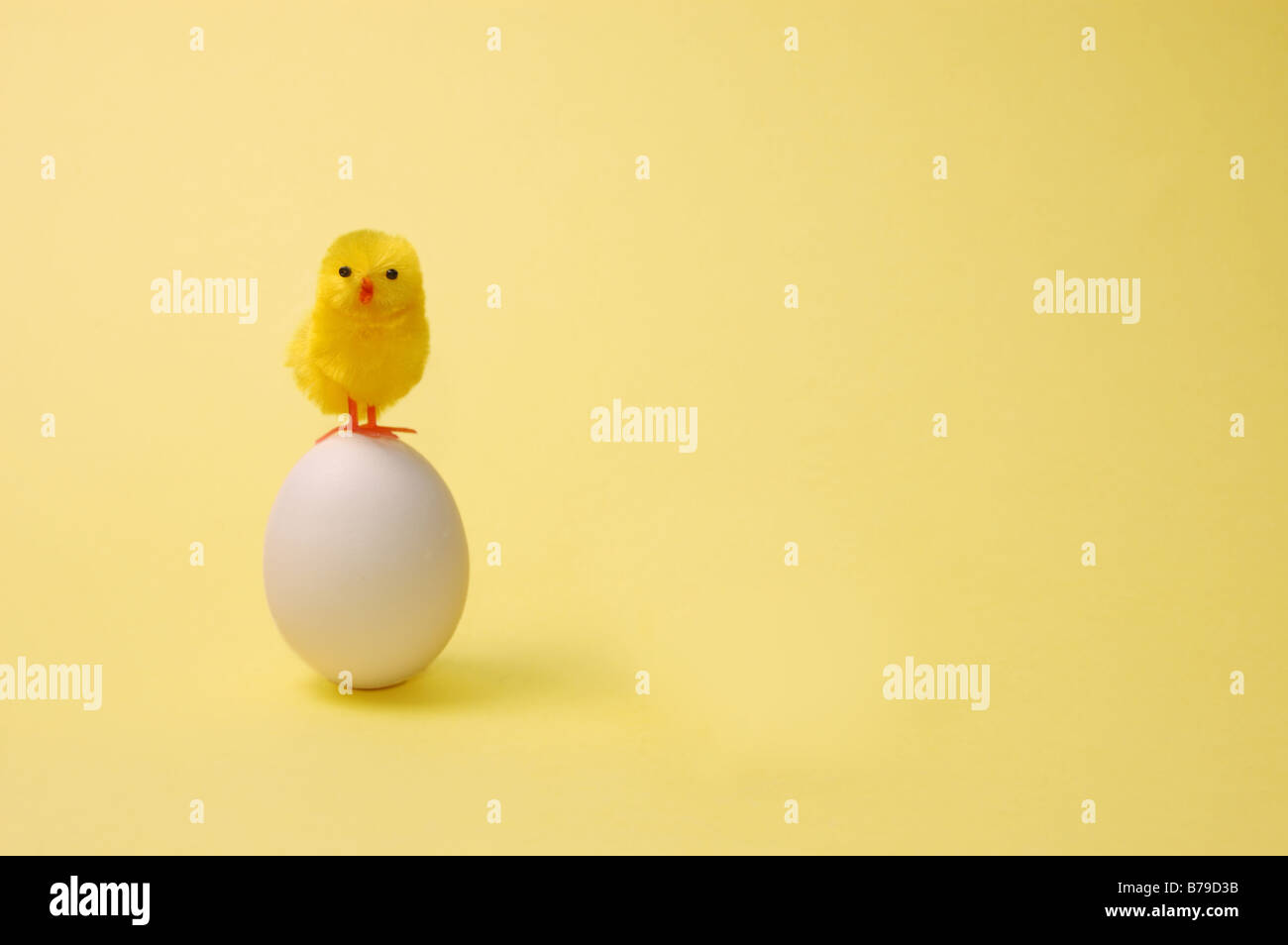 Bild von Spielzeug Küken mit einem Ei mit gelbem Hintergrund Stockfoto