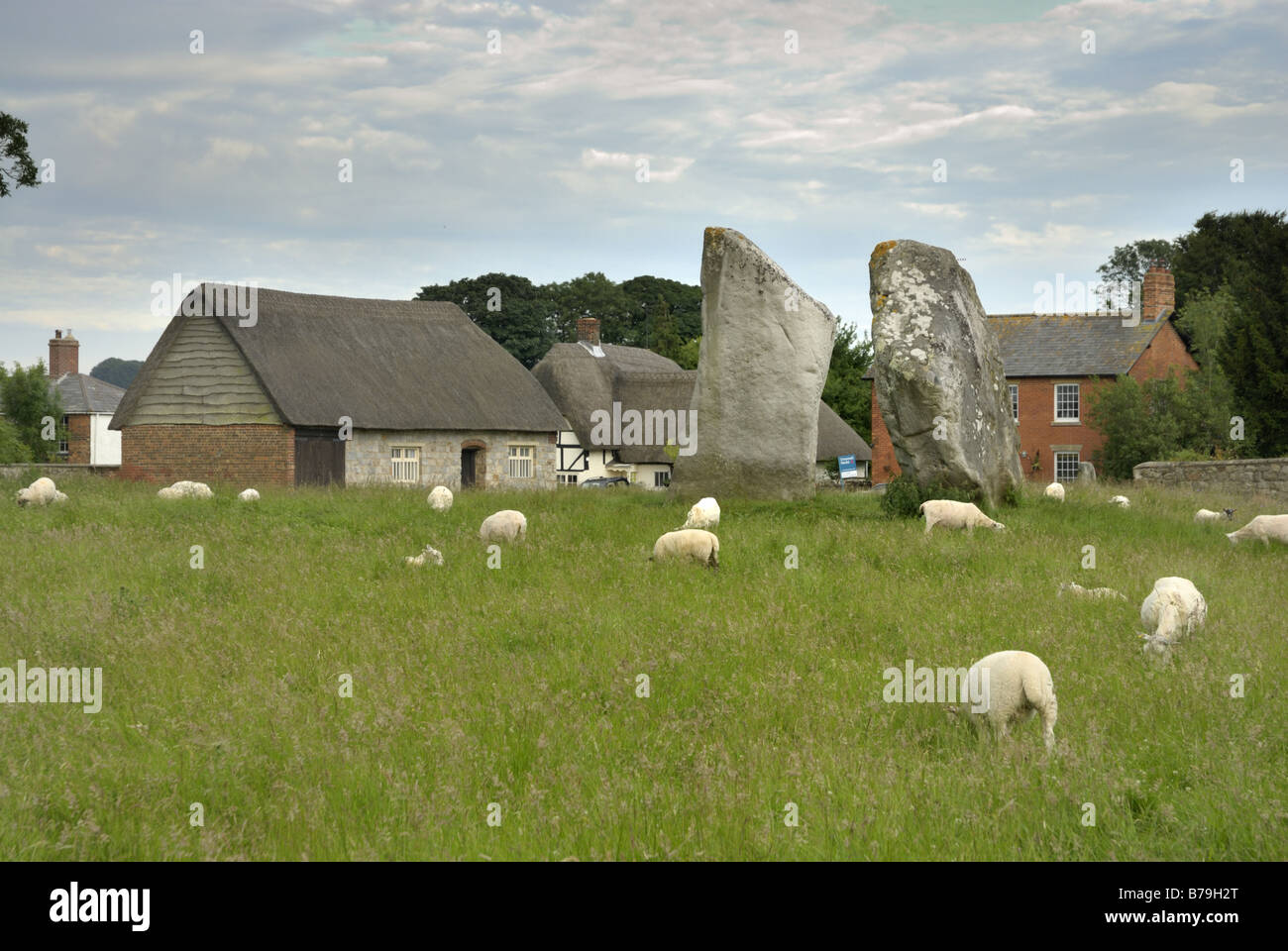 Monolithischen Steinen in Avebury mit Schafe weiden in der Nähe und einige Häuser und Gebäude des Dorfes Avebury im Hintergrund Stockfoto